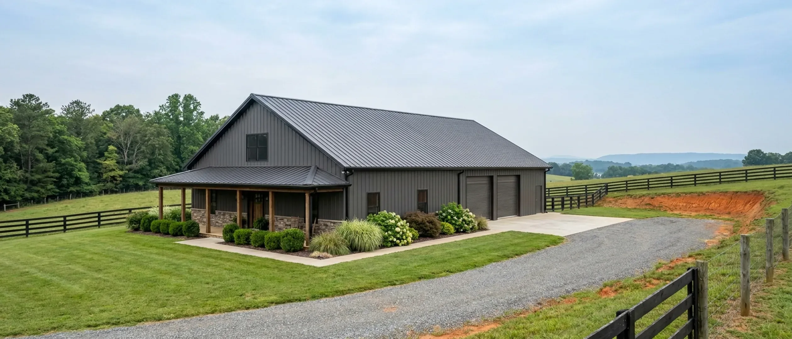 A completed barndominium with a covered entry porch and an attached shop bay, photographed in flat overcast daylight.
