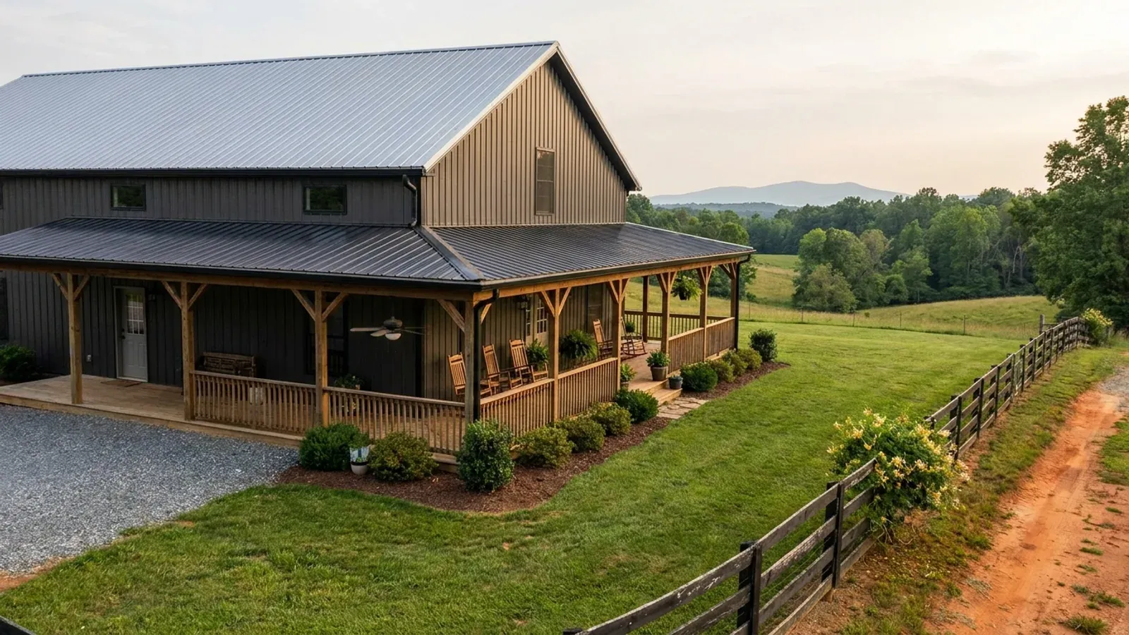 A barndominium exterior showing a deep wrap-around covered porch with posts and railing along two sides of the building.
