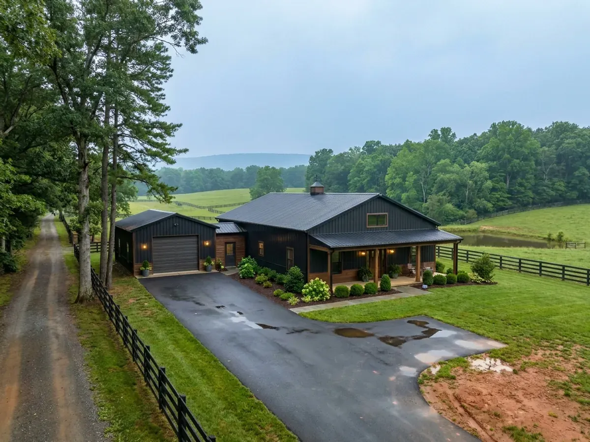 A completed barndominium home viewed from the front corner, with finished landscaping, a covered entry porch and an attached shop bay.